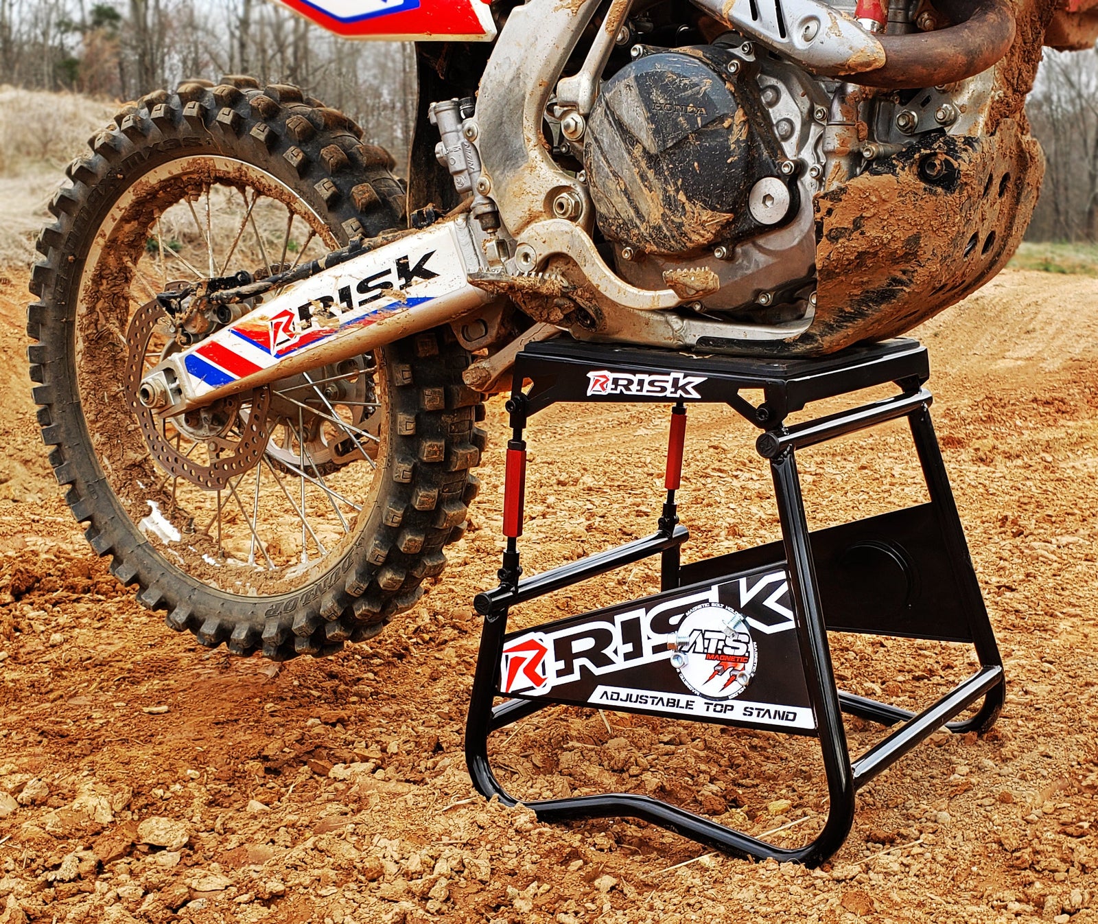 RISK Racing A.T.S. Stand in it's natural habitat at a motocross track with a dirt bike resting level on top of it.